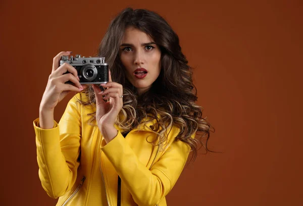 スタジオポートレートの美しい 驚きの女の子で黄色のジャケットにレトロカメラ — ストック写真