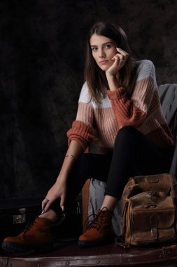 Eski deri ceketli ve bavullu güzel bir kızın stüdyo portresi.