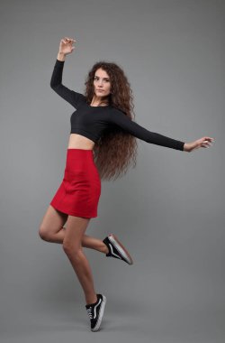 Gri arka planda atlayan güzel bir kızın stüdyo portresi.