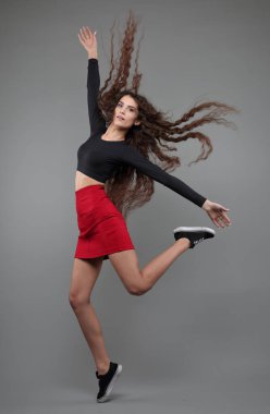 Gri arka planda atlayan güzel bir kızın stüdyo portresi.