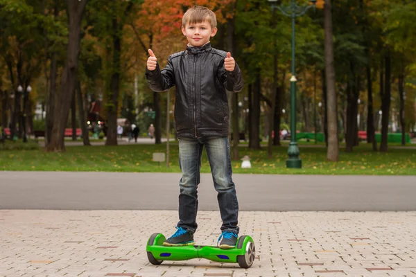 Szczęśliwy chłopiec stojący na hoverboard lub gyroscooter odkryty. — Zdjęcie stockowe