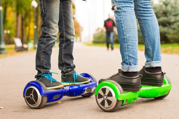 英尺的女孩和男孩骑电动迷你赛格威户外在公园. — 图库照片