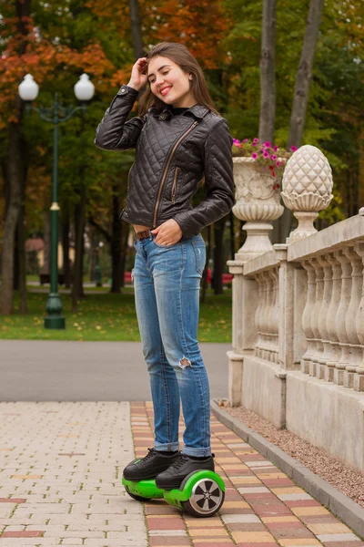 Счастливая девушка, стоящая на ховерборде или гироскутере на открытом воздухе . — стоковое фото