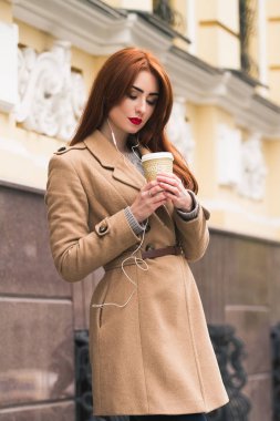 Bir sokakta bir kahve ile zarif kadın bir ceket. Müzik dinleme. Günaydın