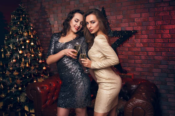Two young women dancing in dress with a champagne at club on New Year.