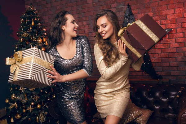 Duas lindas jovens mulheres dão presentes de Natal e dançam no clube. Festa de Natal . — Fotografia de Stock