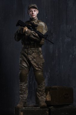 Bir tüfekle kutuları üzerinde duran delikanlı. Kendinden emin ve gurur bakmak