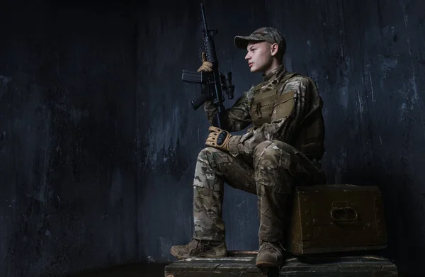 Joven soldado sentado en cajas de rifle y con confianza mira hacia adelante.Los soldados - nuestro orgullo — Foto de Stock