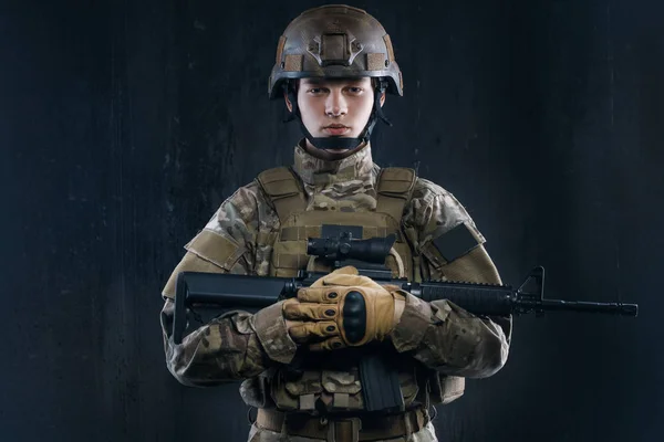 Airsoft - um jogo para homens reais. Forças especiais soldado com rifle no fundo escuro . — Fotografia de Stock