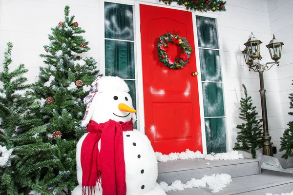 De kroon van Kerstmis met kerstballen, kegels en groenblijvende takken op een rode deur. — Stockfoto