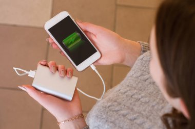 Kız el akıllı telefon ve güç banka içinde tutun. Güç bankadan akıllı telefon şarj. 