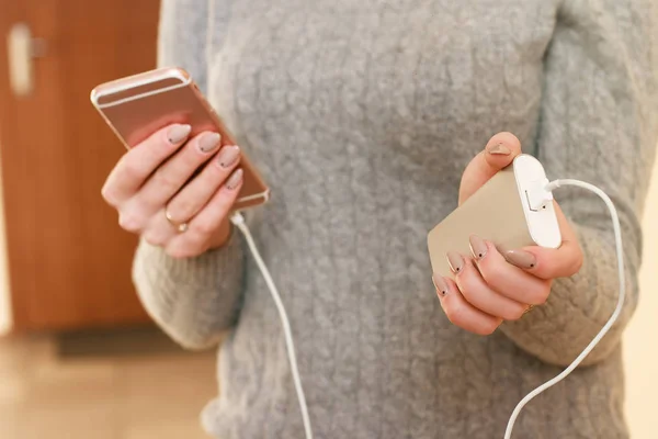 Женщина играет в мобильные игры на смартфоне на работе. Зарядить смартфон от банка питания . — стоковое фото
