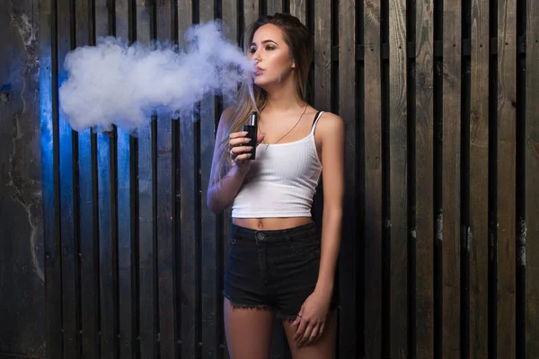 Jovem mulher bonita fumando (vaping) e-cigarro com fumaça . — Fotografia de Stock