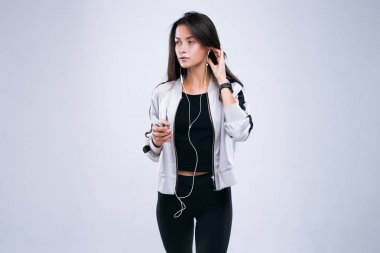 Raslantısal spor eğitim onun elinde earphones ve cep telefonu ile başlar. Ayakta gri arka plan üzerinde izole Studio