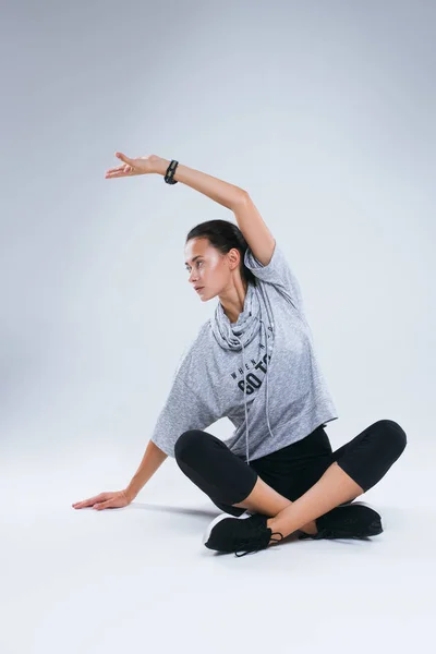 Hermosa joven deportista haciendo ejercicios de yoga y levantó la mano mientras estaba sentada en el fondo blanco en el estudio . —  Fotos de Stock