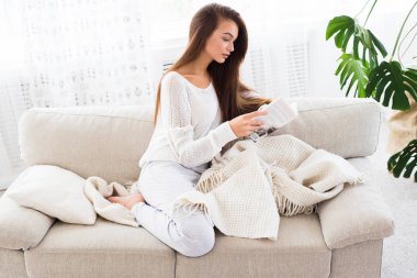 İyi kitap içinde dalmış. Güzel genç kadın evde kanepede otururken bir kitap okuma