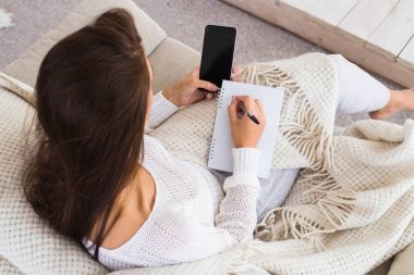 çekici esmer kadın denetim listesi ve evde otururken cep telefonu kullanma yazmak.