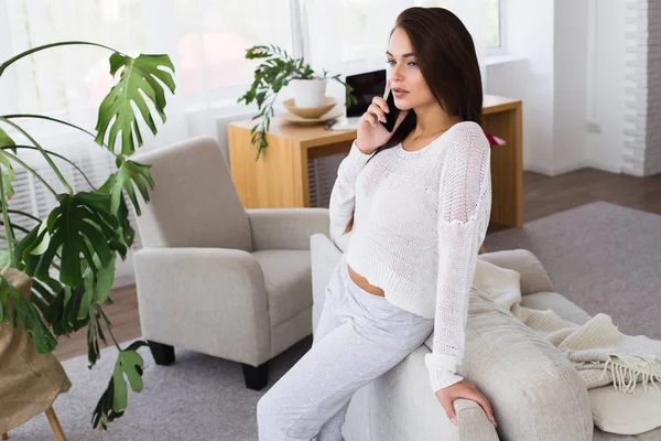 Konuşma tadını çıkarın. Antrenöre evde yaslanmış iken cep telefonda konuşurken çekici genç kadın