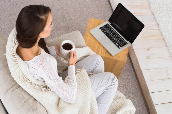 Наслаждайтесь утренней чашкой кофе или чая. Красивая женщина смотрит на экран ноутбука и смотрит утренние новости . — стоковое фото