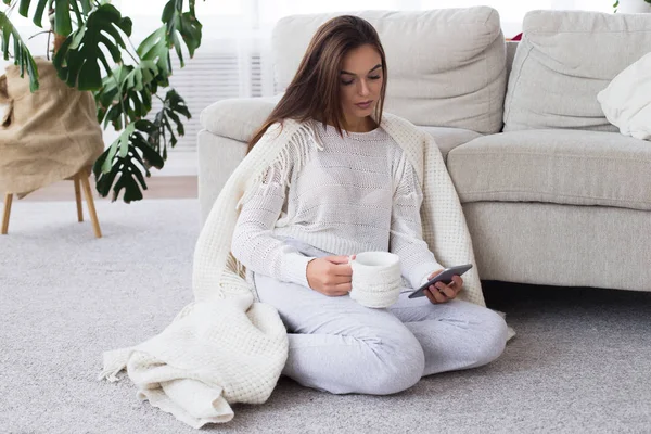 De bonne humeur. Belle jeune femme regardant sur le téléphone portable et tapant un message à des amis. Profitez d'une tasse de café du matin — Photo