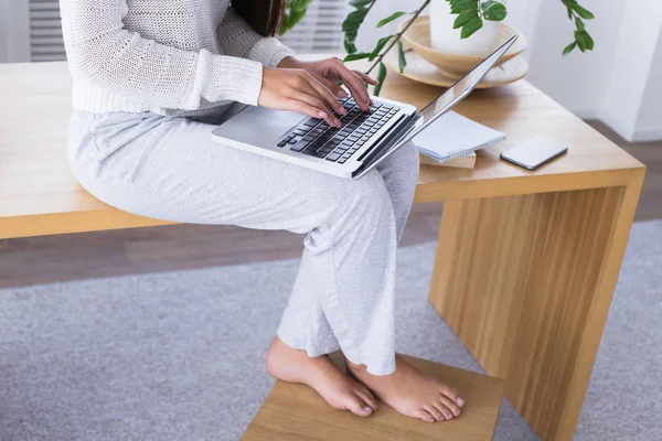 Красивые женские ноги. Молодая женщина печатает на компьютере. Женщина сидит за столом с компьютером и работой — стоковое фото