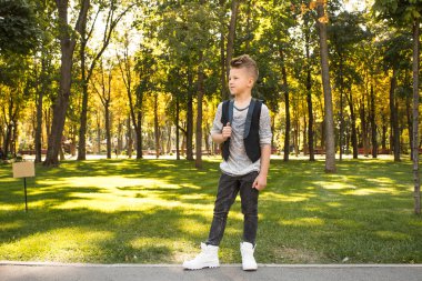 Güzel çocuk giysi ve parkta kalırken gülümseyen düzelt