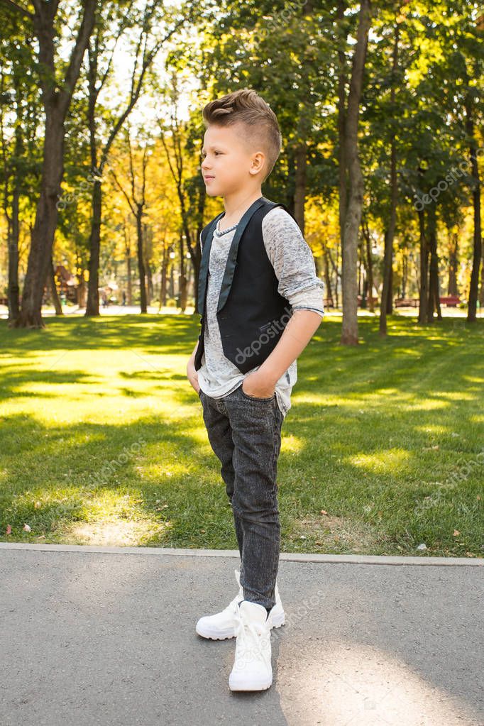 Niño de moda en ropa casual caminando por el parque y mirando