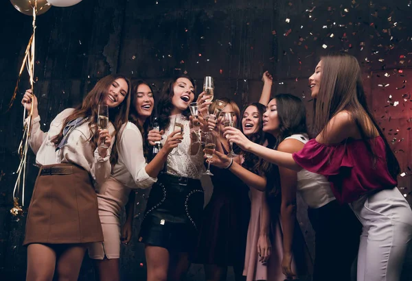 Девушки загадывают новогоднее желание и пьют шампанское. Счастливая группа привлекательных девушек, танцующих с бокалами шампанского — стоковое фото