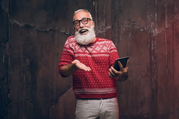Feliz hombre mayor se comunica a través de la comunicación de vídeo con los familiares y gesticula en un suéter de Navidad . —  Fotos de Stock