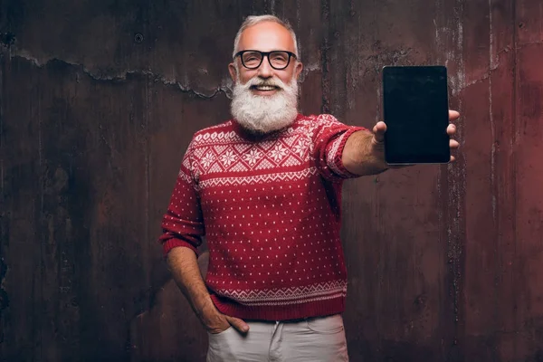 Hombre mayor feliz moderno muestra teléfono inteligente y sonrisas. Santa Claus desea Feliz Navidad —  Fotos de Stock