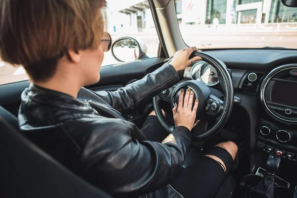 Imagen recortada de una chica conduciendo un coche, manos en el volante. Chica hace clic en la señal — Foto de Stock