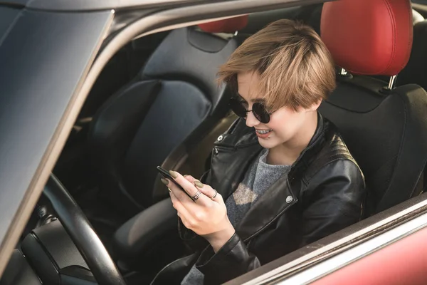 Mujer de negocios que utiliza Internet en su teléfono móvil y s mientras está sentado en el coche. Noticias en internet. Trabaja duro en todas partes — Foto de Stock