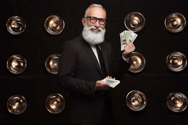 El hombre barbudo feliz lleva muchos billetes de dólares y sonríe, vistiendo en ropa formal y gafas de moda. Mirando a la cámara. Premio Happy of money . —  Fotos de Stock