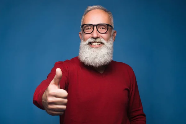 Happy modern old bearded man in warm sweeter show thumb up and happy smiling. Isolate on blue background. Successful and handsome adult bearded man of enjoying him emotions. Show ok and happy emotions — Stock Photo, Image