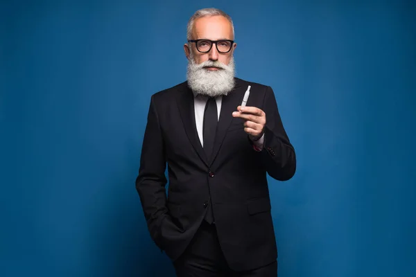Бородатый бизнесмен курит электронную сигарету в костюме. Новая технология здорового курения электронных сигарет . — стоковое фото