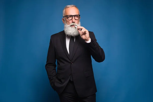 Hombre de negocios barbudo fumando cigarrillo electrónico en el traje. Nueva tecnología de tabaquismo saludable del cigarrillo electrónico de vapeo . — Foto de Stock