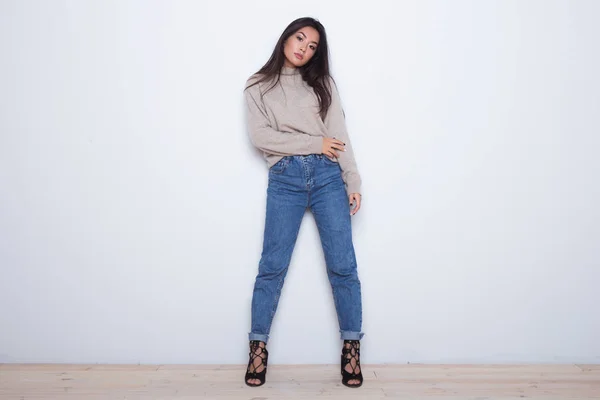 Fashion posing beautiful Asian girl in trendy wearing. Casual wearing in jeans, high heel shoes and sweeter