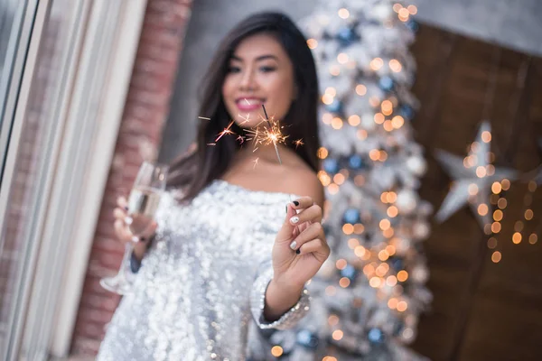 Beautiful girl with a fireworks in her hand dancing on the club, fun and waiting for Christmas time. Ready to celebrate. Confetti and fireworks. Christmas party