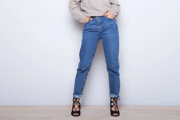 Jeans di moda su una ragazza. Gambe sottili di ragazza di moda. Gambe femminili a forma di tacco alto scarpe e jeans vicino a una parete bianca — Foto Stock