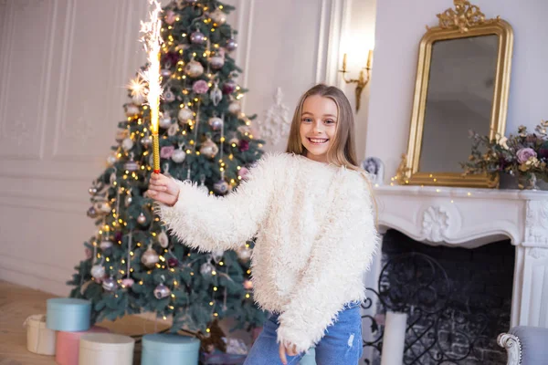 Красивый ребенок с фейерверком в руках на фоне рождественской елки. Рождественская концепция — стоковое фото