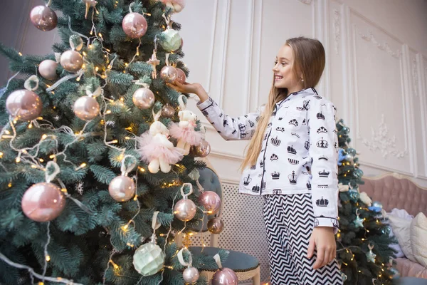 Красивая счастливая улыбающаяся девушка украшает елку в помещении. Концепция подготовки к новому году . — стоковое фото