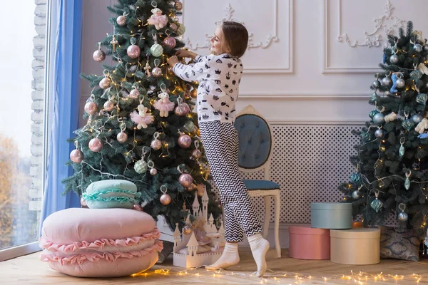 Hermosa chica sonriente feliz está decorando el árbol de Navidad en el interior. Concepto de preparación para el nuevo año . —  Fotos de Stock