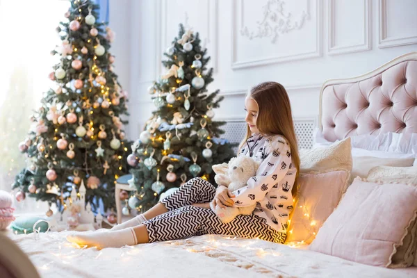 Joyeux petite fille avec un joli jouet sur un fond d'arbres de Noël. Le meilleur cadeau pour Noël. Le lendemain de Noël. Joyeux Noël et Joyeuses Fêtes ! — Photo