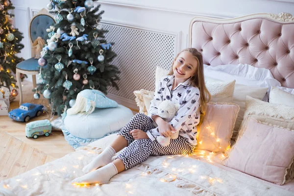 Noel ağaçları bir arka plan üzerinde güzel bir oyuncakla mutlu küçük kız. En iyi hediye Noel için. Noel sabahında. Mutlu Noeller ve mutlu tatiller! — Stok fotoğraf