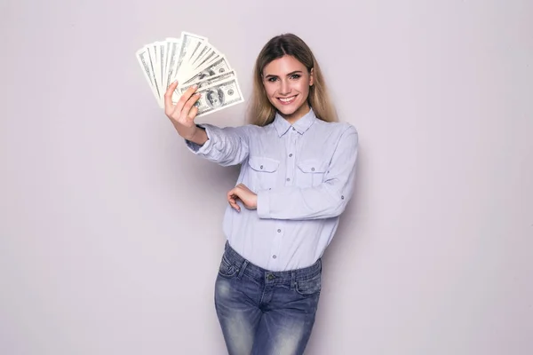 Bild einer glücklichen jungen Geschäftsfrau, die über einer grauen Wand steht und Geld hält. Kamera gesucht. — Stockfoto