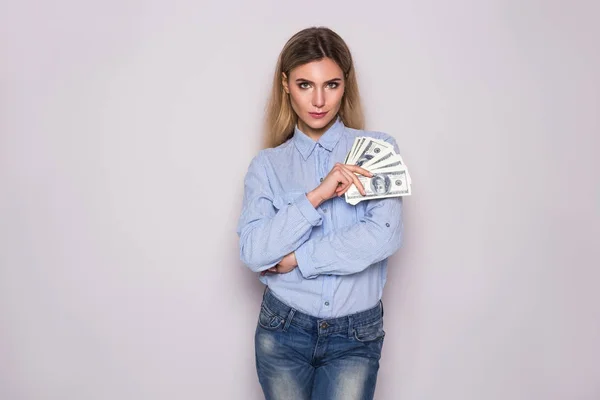Bild einer ernsthaften jungen kaukasischen Frau, die isoliert vor grauem Hintergrund steht. Kamera gesucht und Geld in der Hand. — Stockfoto