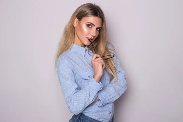 Retrato de una mujer encantadora sosteniendo gafas y mirando a la cámara. Posando sobre fondo gris — Foto de Stock