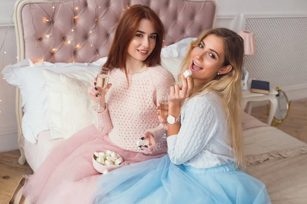 Duas raparigas estão sentadas na cama. Eles estão falando, comendo marshm — Fotografia de Stock
