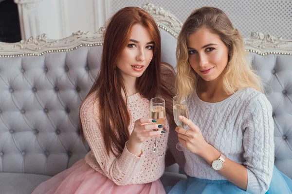 Zwei Mädchen sitzen auf dem Sofa und umarmen sich. sie trinken — Stockfoto
