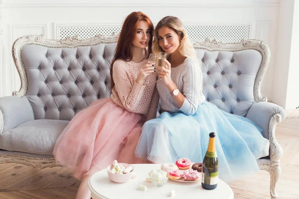 Zwei Mädchen sitzen auf dem Sofa und umarmen sich. sie trinken — Stockfoto